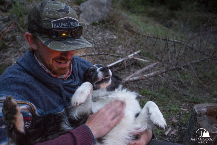 Man and Borer Collie dog relaxing and smiling around campfire while camping.