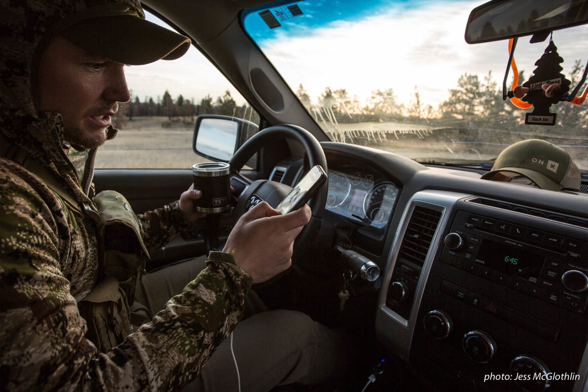 Man looking at onX Hunt map on phone while in truck.
