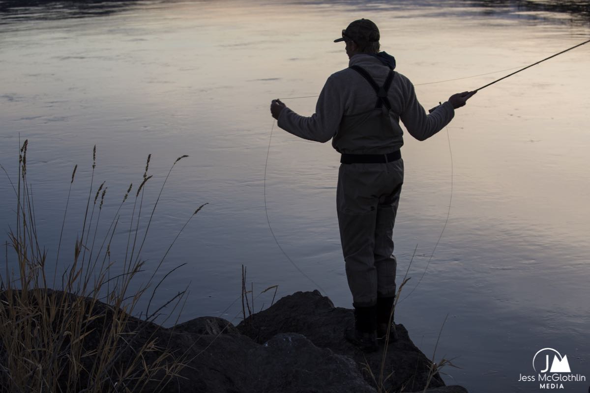 Man casting a fly rod on the Missouri River at dusk.