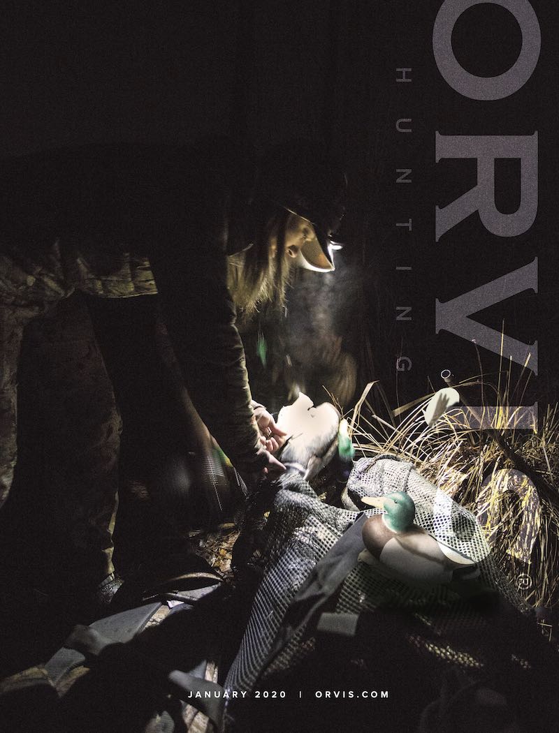 Woman putting out duck hunting decoys in the dark while waterfowl hunting in Pennsylvania, cover of Orvis Hunt catalog.