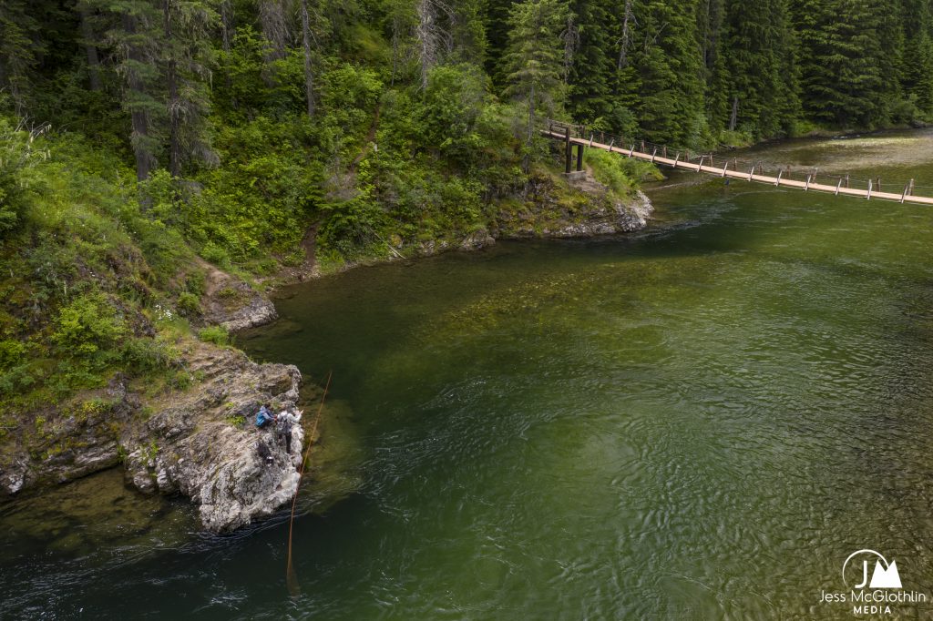 Drone photograph of two anglers and a dog fishing a clear river in Idaho.