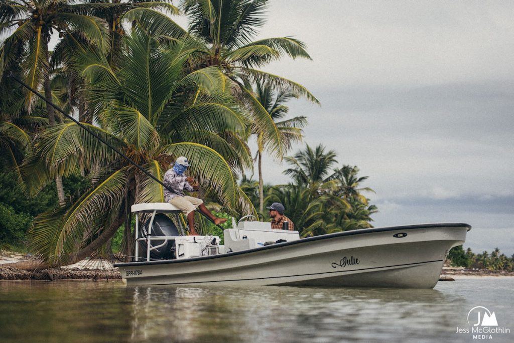 Two men talking on a flats fishing panga boat in Belize while fly fishing.