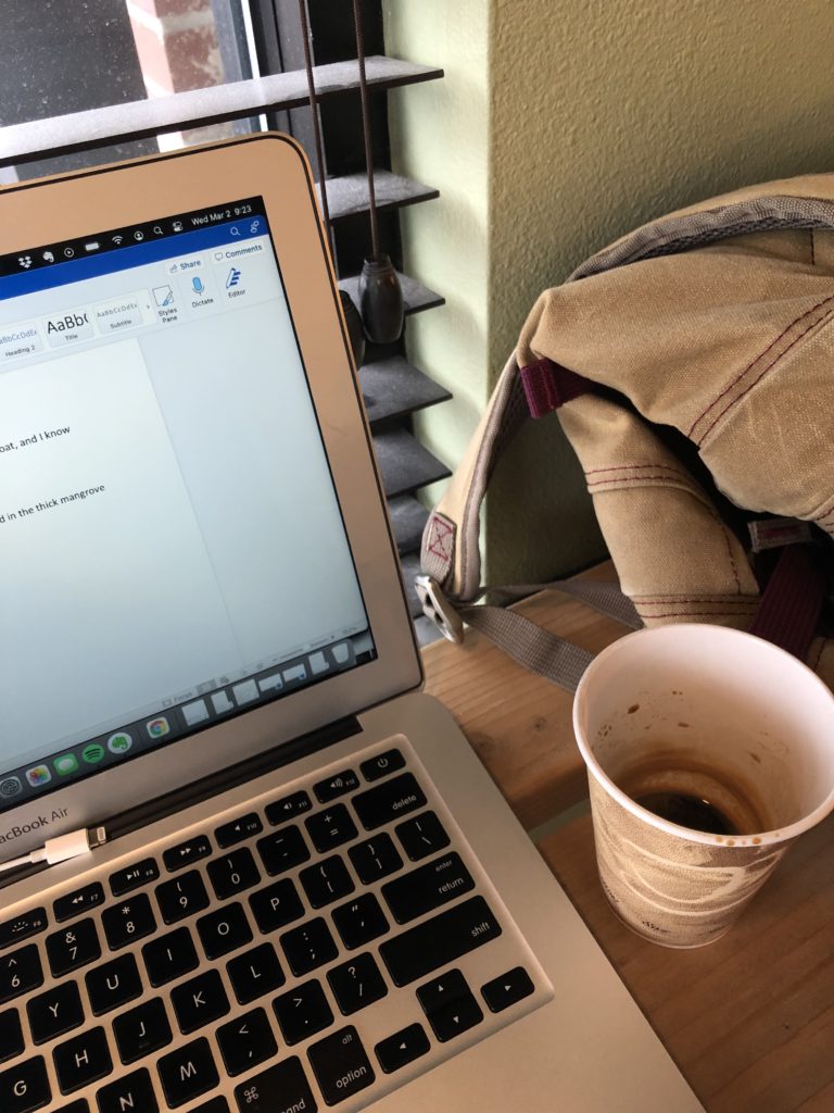 Laptop, cup of coffee, and backpack writer working in a coffeeshop.